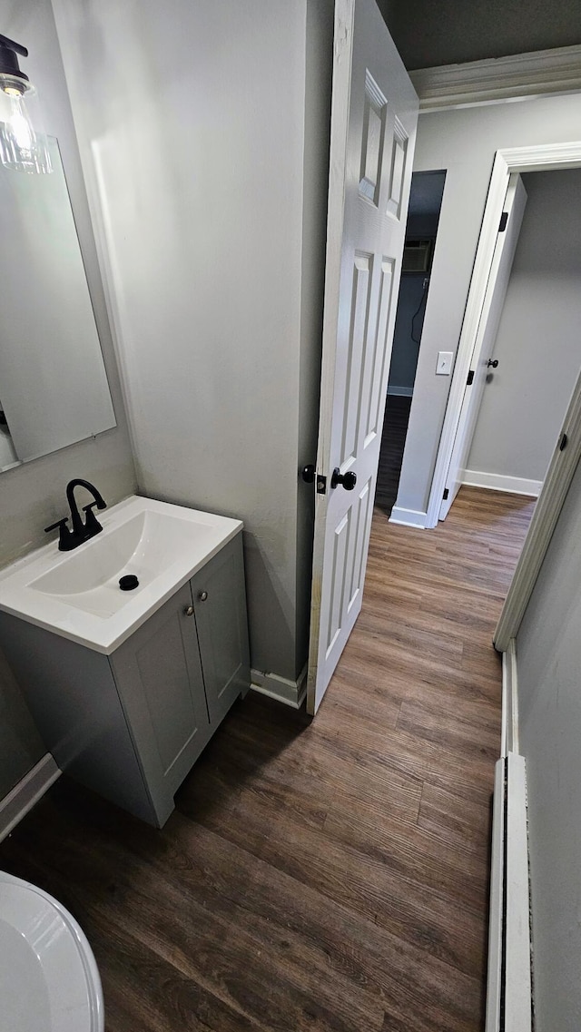 bathroom with a baseboard radiator, vanity, baseboards, and wood finished floors