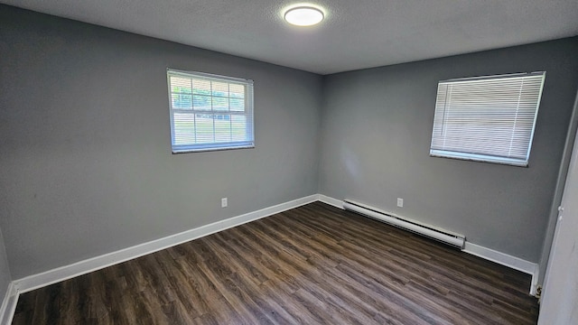 unfurnished room featuring dark wood-type flooring, baseboard heating, and baseboards