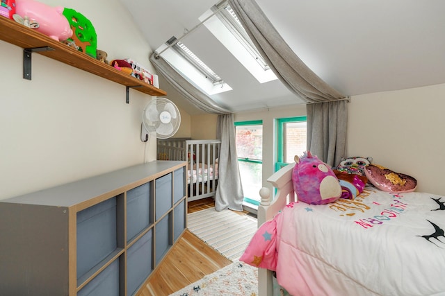 bedroom with vaulted ceiling with skylight and light wood-style floors