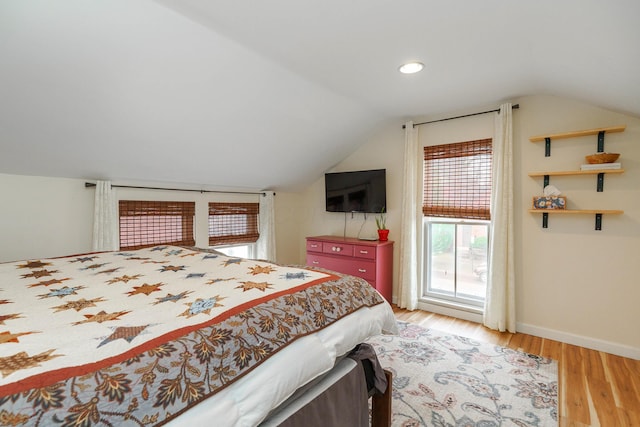 bedroom featuring light wood finished floors, vaulted ceiling, and baseboards