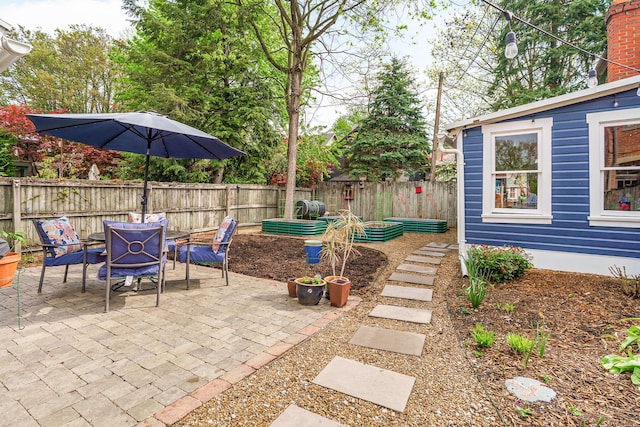 view of patio featuring a garden, outdoor dining space, and a fenced backyard