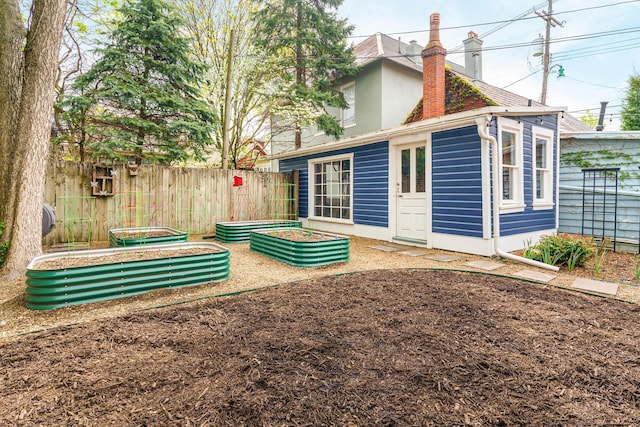 back of property featuring a garden, fence, and a chimney