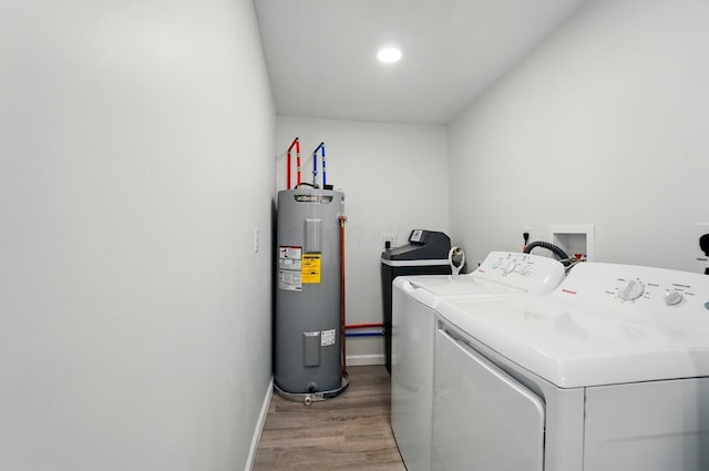 clothes washing area featuring water heater, baseboards, light wood-style floors, independent washer and dryer, and laundry area