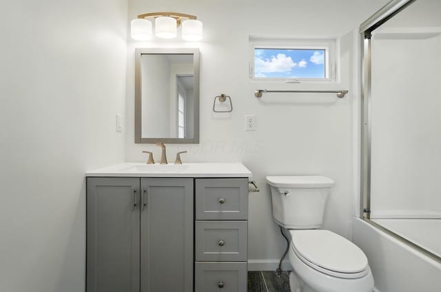 bathroom with toilet, enclosed tub / shower combo, vanity, and baseboards