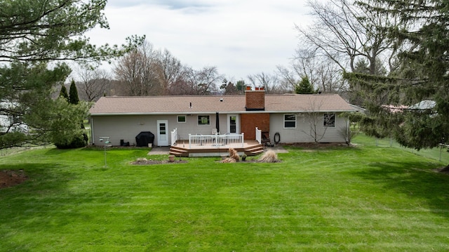 back of property with a wooden deck, a chimney, and a lawn