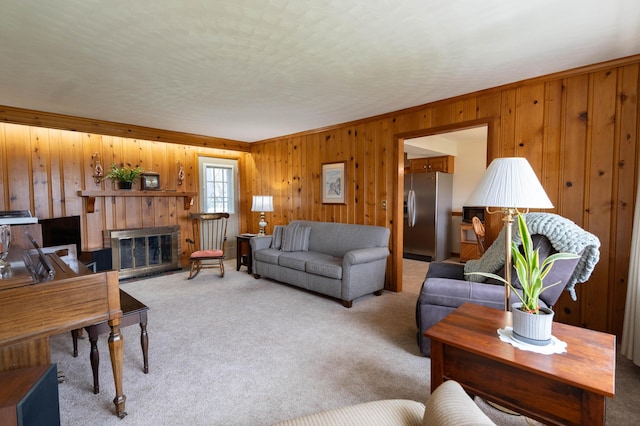 carpeted living area with wooden walls, crown molding, and a fireplace