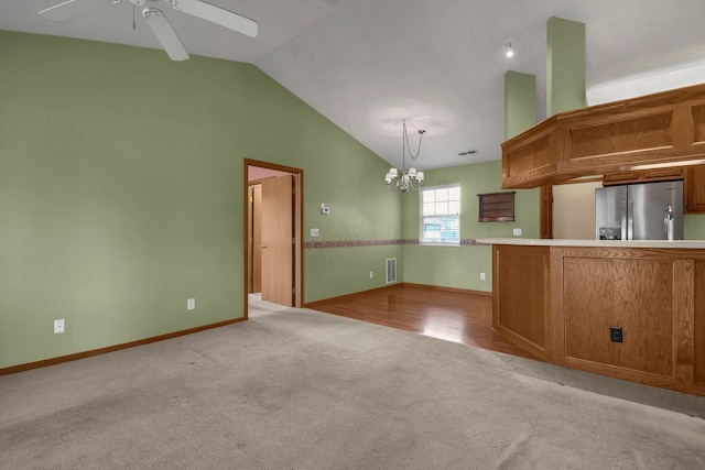 kitchen featuring ceiling fan with notable chandelier, stainless steel fridge, light countertops, light colored carpet, and visible vents