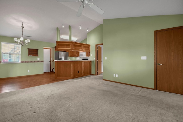 kitchen featuring lofted ceiling, stainless steel fridge with ice dispenser, white microwave, brown cabinetry, and light colored carpet