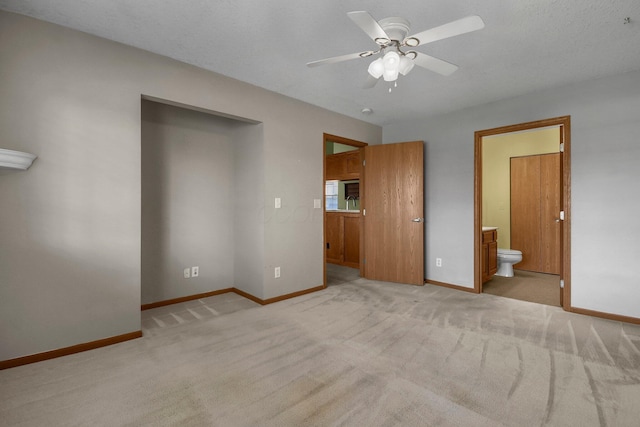 unfurnished bedroom featuring connected bathroom, baseboards, ceiling fan, and light colored carpet