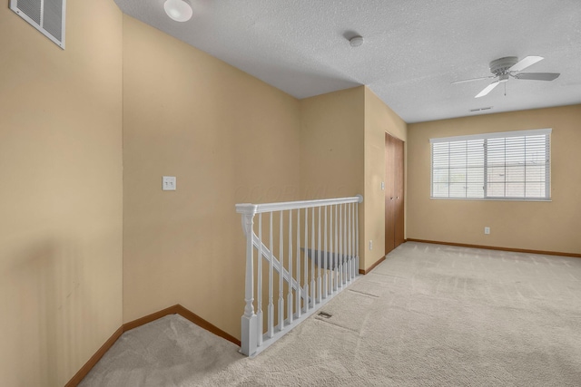 spare room with a ceiling fan, a textured ceiling, carpet, baseboards, and visible vents