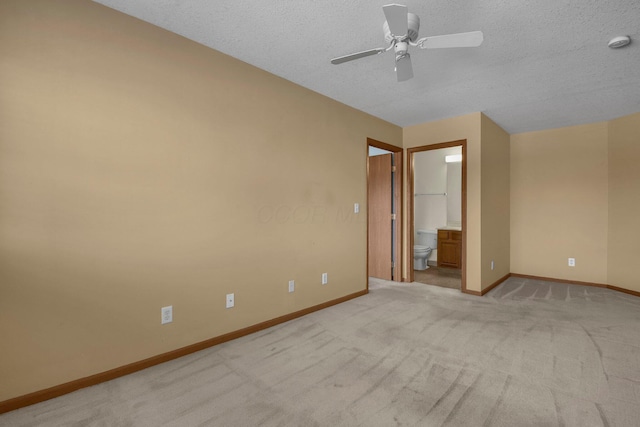 unfurnished bedroom featuring a ceiling fan, light carpet, ensuite bath, baseboards, and a textured ceiling