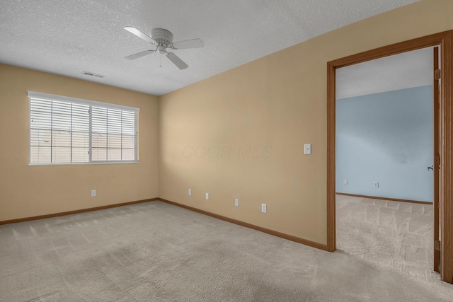 unfurnished room featuring carpet flooring, a textured ceiling, visible vents, baseboards, and a ceiling fan