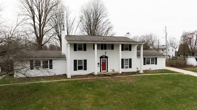colonial inspired home with a chimney and a front lawn