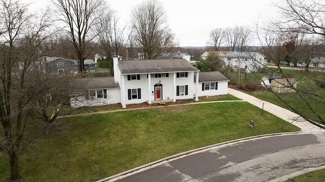 colonial home featuring a chimney, a residential view, and a front yard