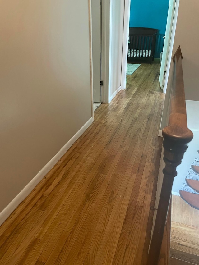 corridor featuring wood finished floors and baseboards