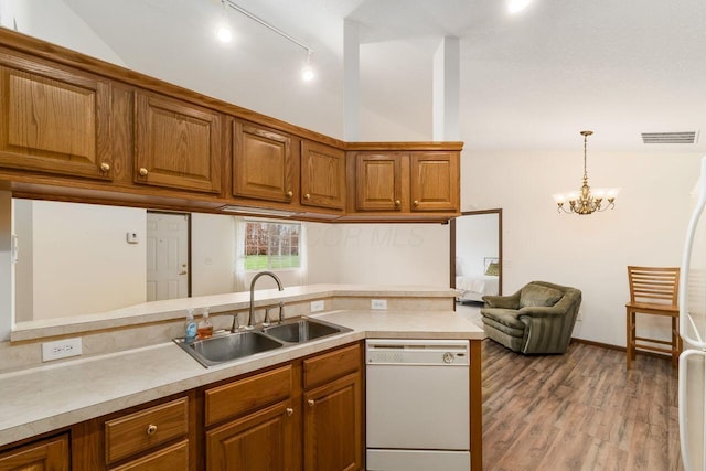 kitchen with white appliances, light countertops, brown cabinets, a sink, and vaulted ceiling