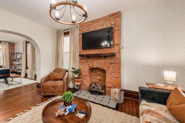 870 Oakwood Ave, Columbus, OH 43206 - living room with wood finished floors, arched walkways, an inviting chandelier, a fireplace, and baseboards