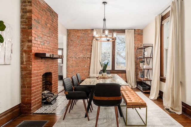 870 Oakwood Ave, Columbus, OH 43206 - dining area featuring visible vents, dark wood-style flooring, baseboards, a brick fireplace, and a notable chandelier