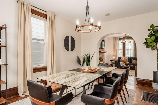 870 Oakwood Ave, Columbus, OH 43206 - dining space featuring a chandelier, arched walkways, wood finished floors, and plenty of natural light