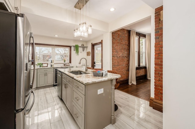 870 Oakwood Ave, Columbus, OH 43206 - kitchen with a kitchen island with sink, a sink, freestanding refrigerator, gray cabinetry, and brick wall