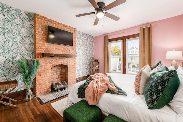 870 Oakwood Ave, Columbus, OH 43206 - bedroom featuring an accent wall, wallpapered walls, a ceiling fan, a brick fireplace, and wood finished floors