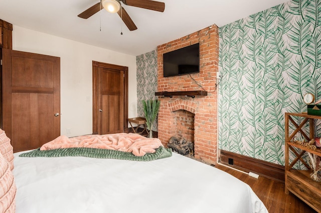 870 Oakwood Ave, Columbus, OH 43206 - bedroom with an accent wall, wood finished floors, wallpapered walls, ceiling fan, and a brick fireplace