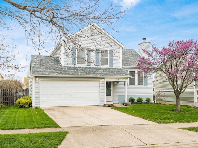 split level home featuring concrete driveway, a chimney, a front yard, fence, and a shingled roof