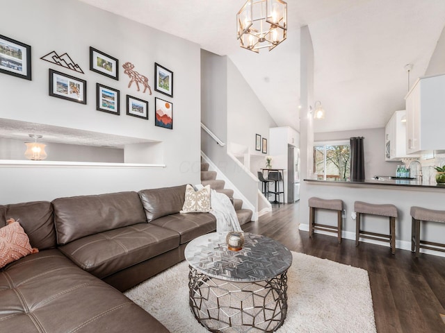 living area featuring baseboards, a notable chandelier, dark wood-style flooring, stairway, and lofted ceiling
