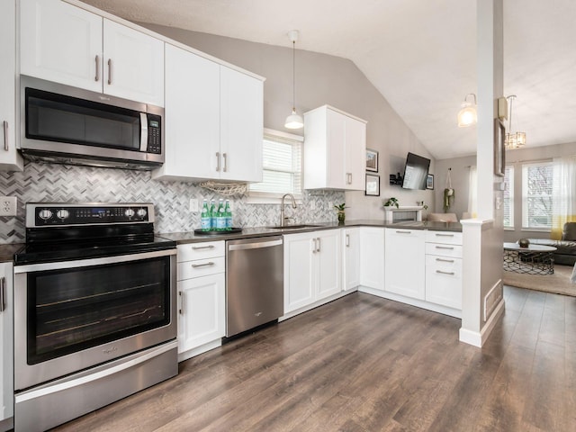 kitchen with dark countertops, a sink, lofted ceiling, and stainless steel appliances