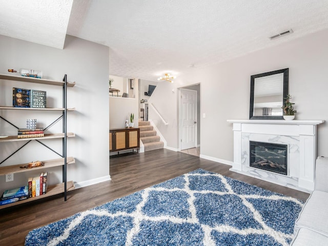 living room featuring a textured ceiling, visible vents, stairway, wood finished floors, and baseboards