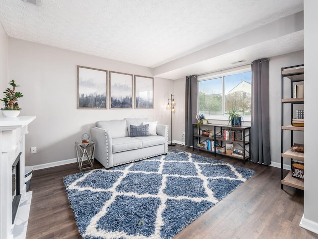 living area featuring a premium fireplace, baseboards, a textured ceiling, and wood finished floors