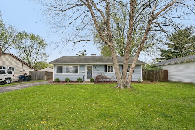 ranch-style home featuring a chimney, a front yard, and fence