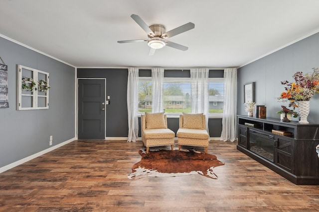 living area with wood finished floors, crown molding, baseboards, and a ceiling fan