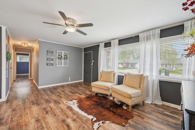 living area with plenty of natural light, a ceiling fan, wood finished floors, and baseboards