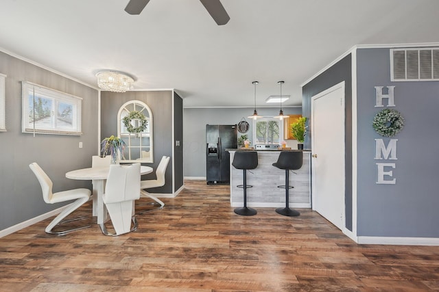 dining space featuring baseboards, wood finished floors, visible vents, and crown molding