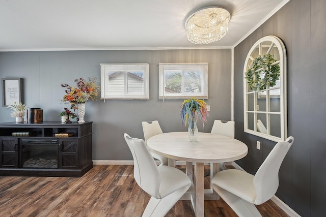 dining room featuring an inviting chandelier, ornamental molding, dark wood-style floors, and baseboards