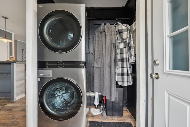 washroom with wood finished floors, stacked washer and clothes dryer, and laundry area