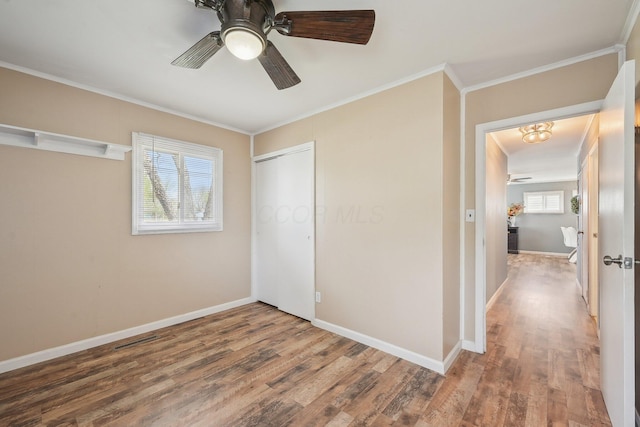 unfurnished bedroom with baseboards, wood finished floors, a closet, and ornamental molding