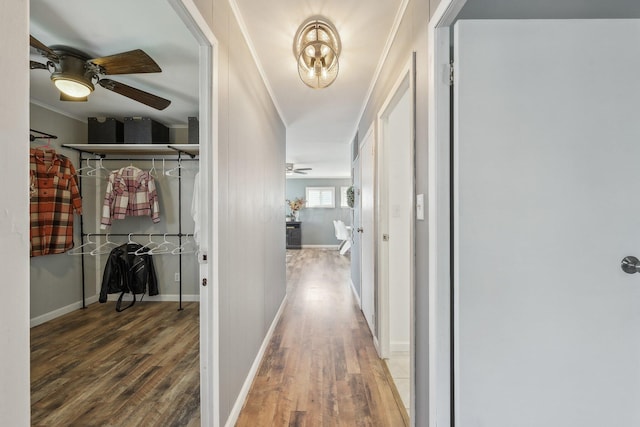 corridor with baseboards, ornamental molding, and wood finished floors