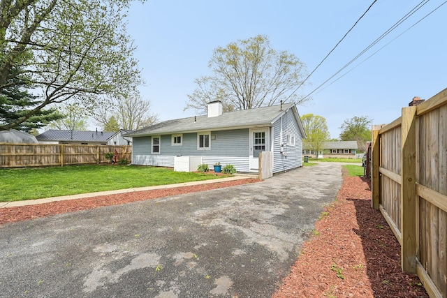 rear view of house featuring fence, a lawn, and a chimney