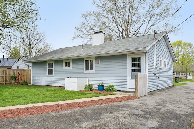back of house featuring a yard, a chimney, and fence