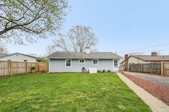 rear view of property with a lawn, a fenced backyard, and a chimney