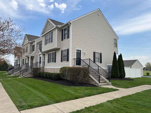 view of home's exterior featuring fence, stone siding, and a lawn
