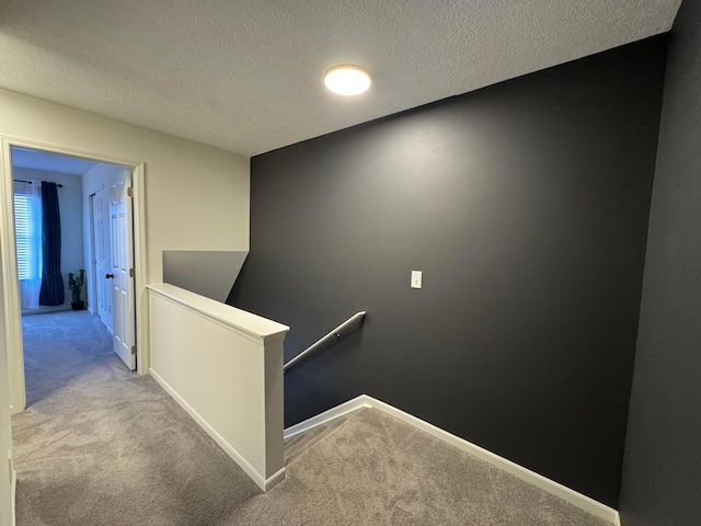 stairway with carpet, a textured ceiling, and baseboards