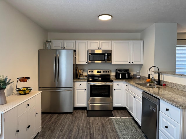 kitchen featuring appliances with stainless steel finishes, dark wood-style flooring, a sink, and white cabinets