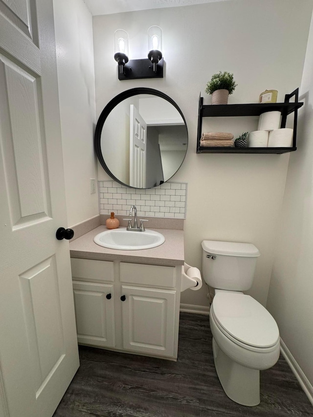 half bathroom featuring toilet, tasteful backsplash, wood finished floors, and vanity