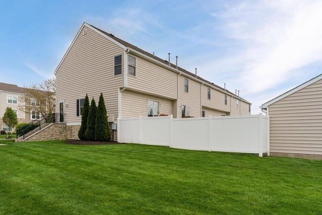 rear view of house featuring fence and a lawn