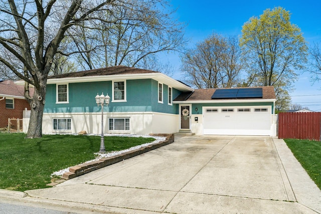 2852 Longfield Rd, Columbus, OH 43204 - view of front of house featuring roof mounted solar panels, stucco siding, an attached garage, driveway, and a shingled roof