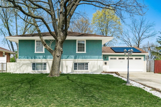 2852 Longfield Rd, Columbus, OH 43204 - split level home with roof mounted solar panels, a garage, concrete driveway, stucco siding, and roof with shingles