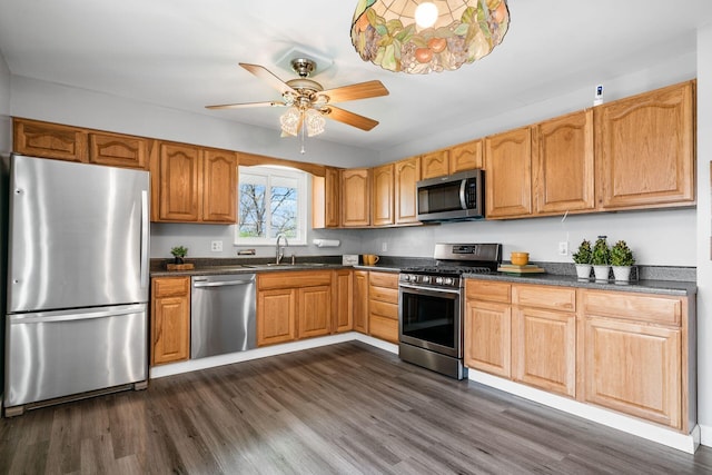 2852 Longfield Rd, Columbus, OH 43204 - kitchen with appliances with stainless steel finishes, dark countertops, dark wood-type flooring, ceiling fan, and a sink